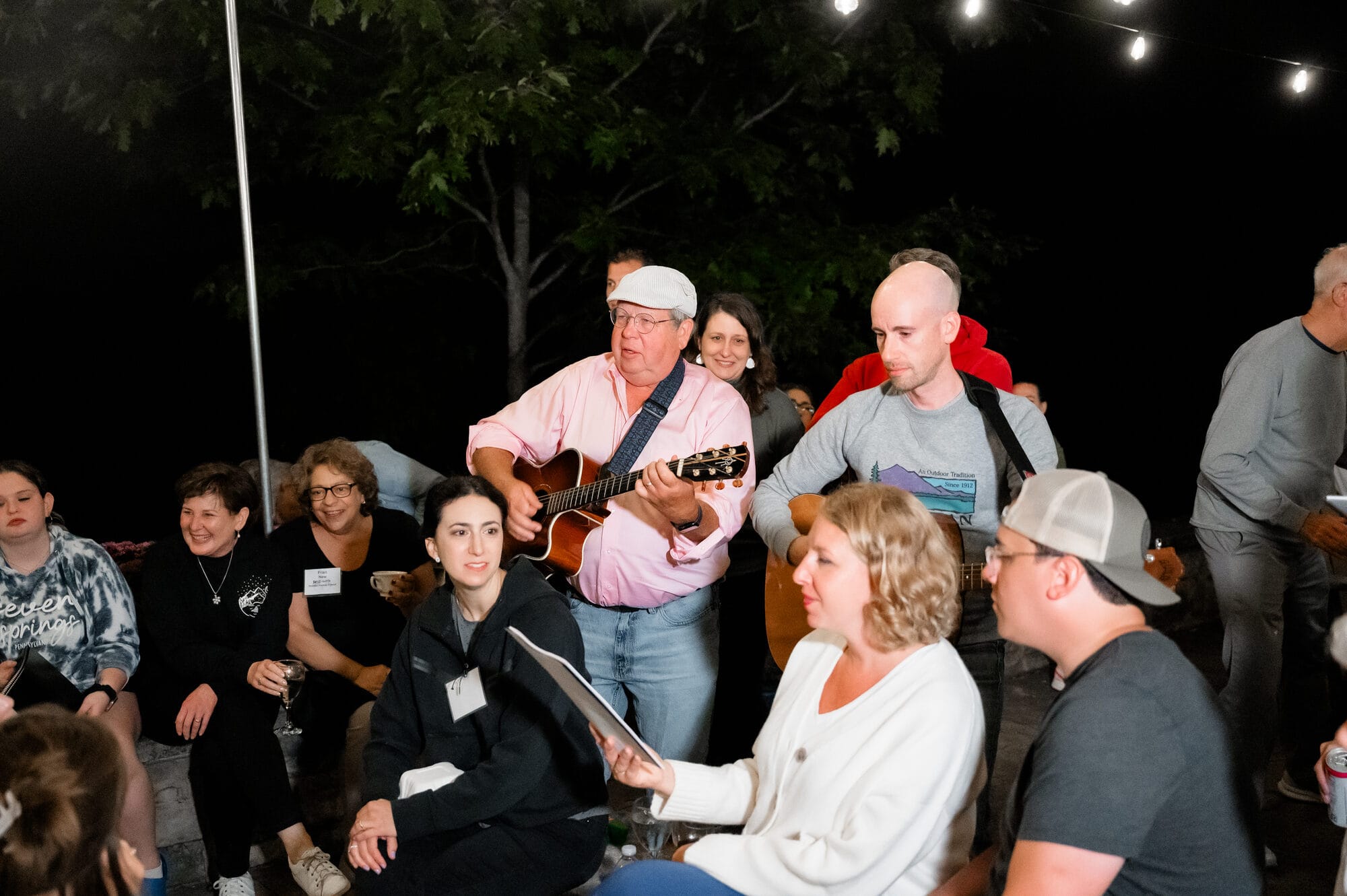 Wedding guests singing together around a fire pit